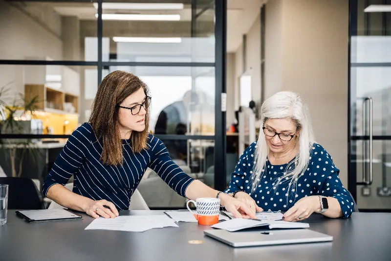 Lisa going through printed material with a colleague at a table