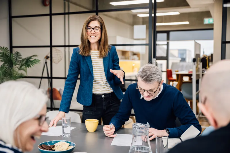 Lisa smiling as she works with a leadership team around a table